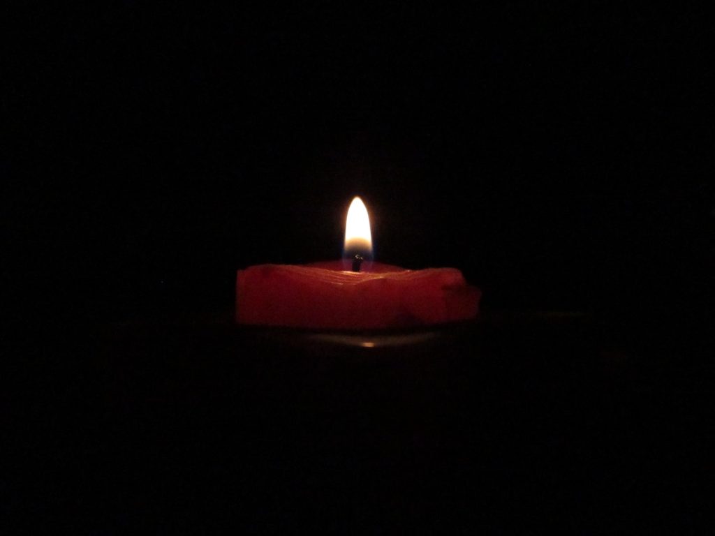 red candle with flame against black background